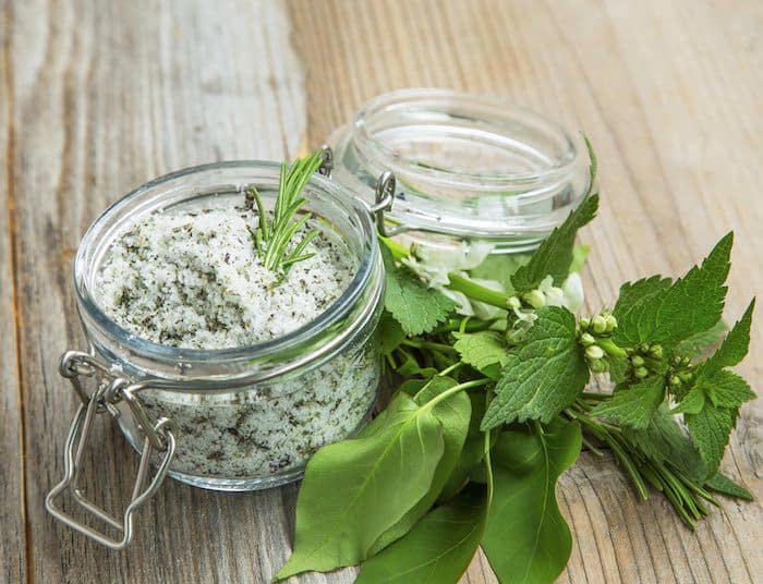 Homemade exfoliator with herbs inside glass jar